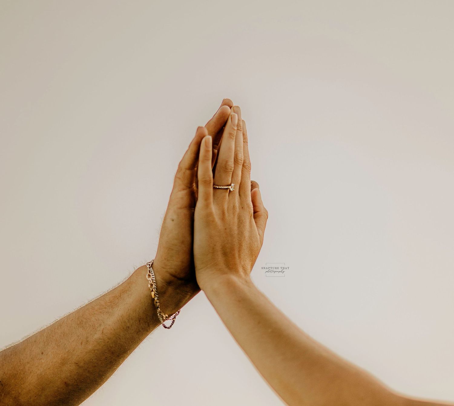 Two hands coming together against white background in artistic pose.