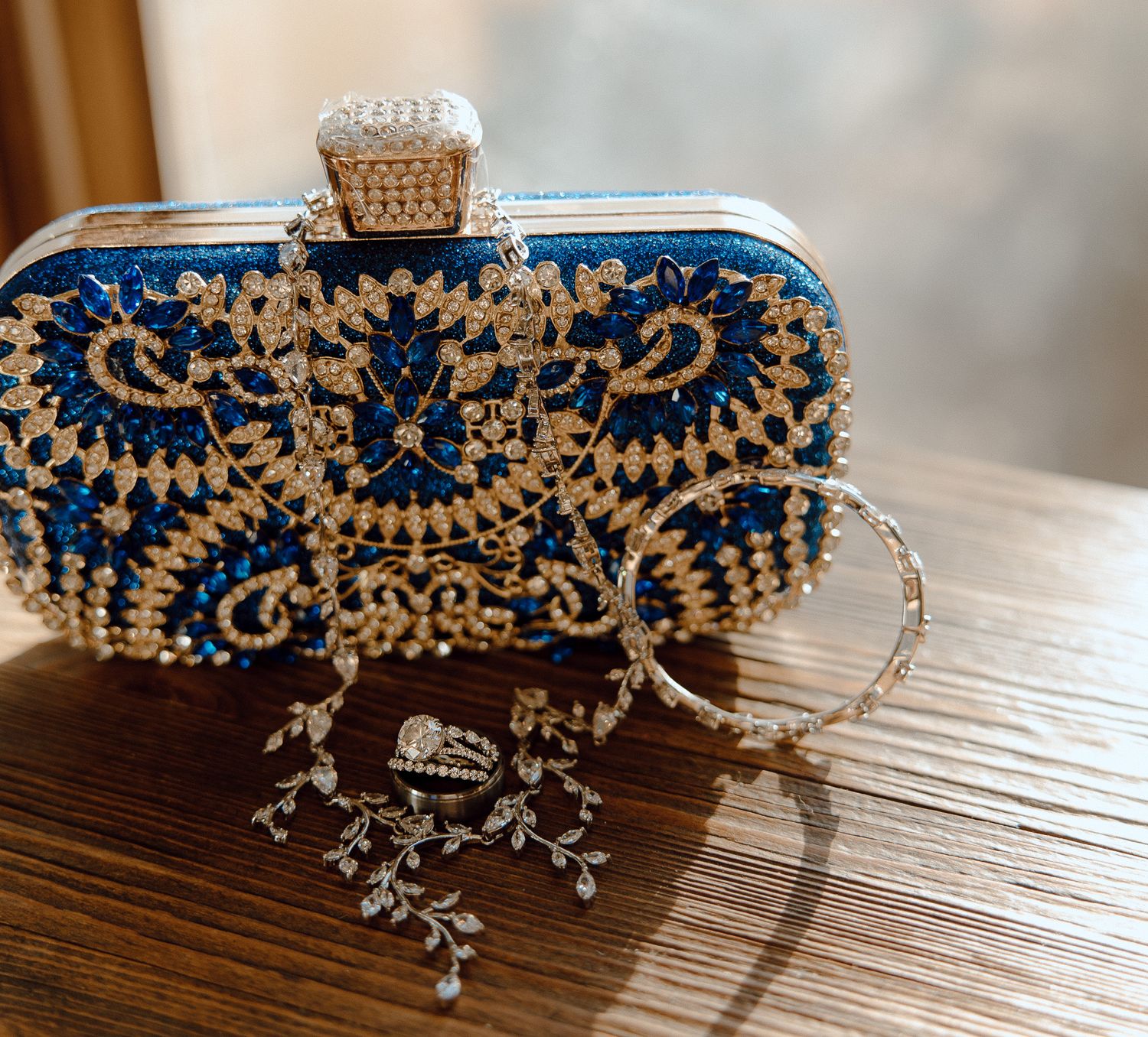 Elegant blue and gold beaded clutch with crystal clasp and delicate jewelry.