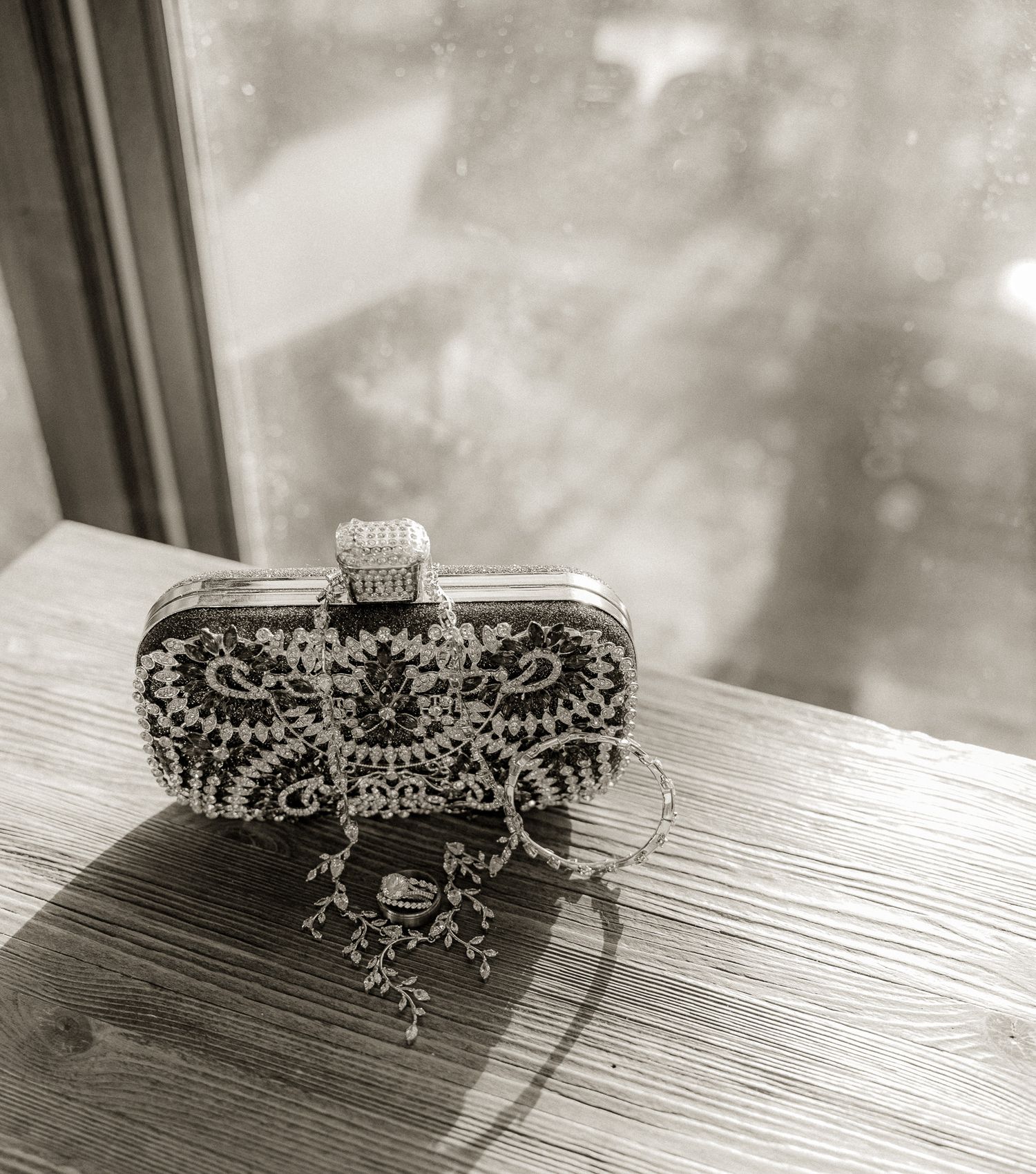 Ornate crystal bridal tiara displayed on wooden surface in black and white photography.