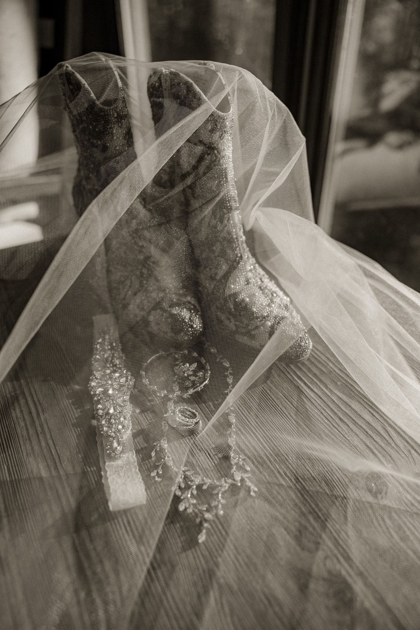 Close-up view of delicate bridal veil with intricate lace details against a wooden surface.