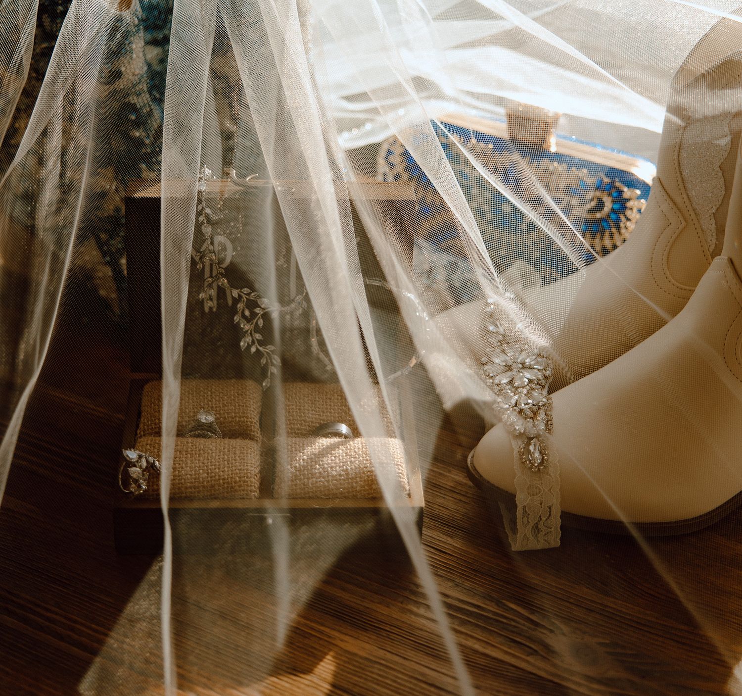 Flowing white wedding veil draped elegantly across wooden floor in natural light.