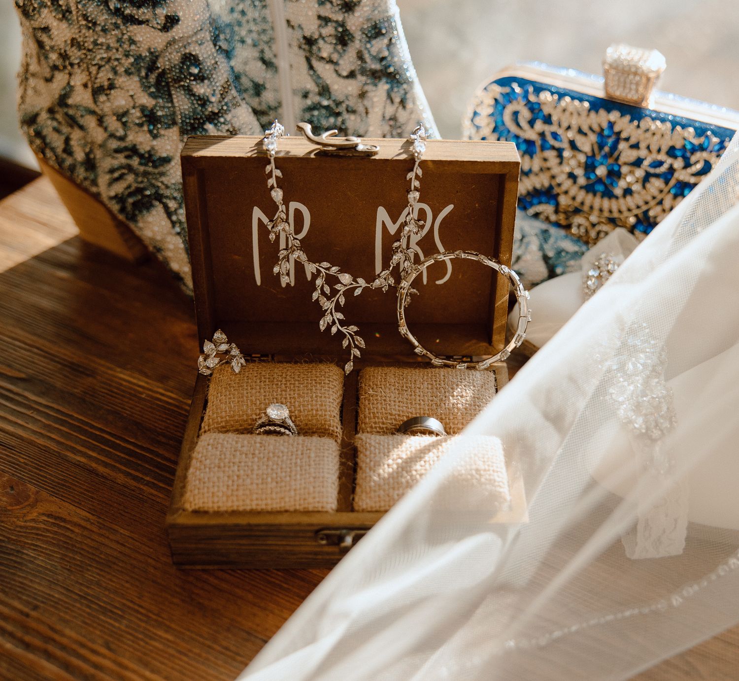 Wedding accessories including earrings and veil arranged on rustic wooden surface.
