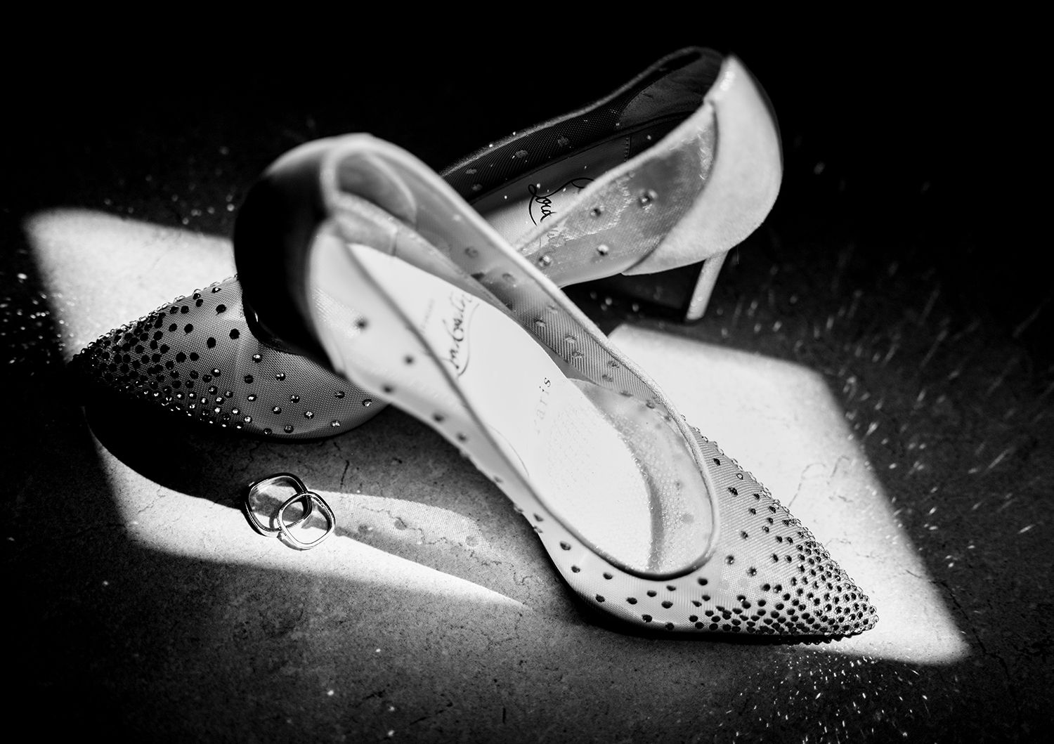 Elegant bridal shoes with crystal details photographed in dramatic black and white.