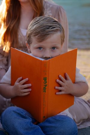 A child peeks over an orange book in a sequence of candid reading photos.