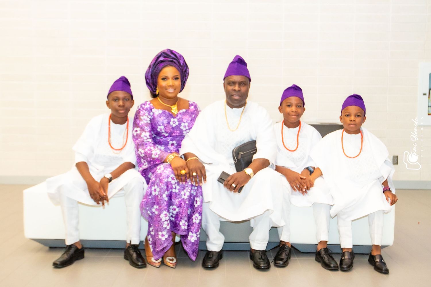 Family photo with people wearing traditional Nigerian attire in purple and white.
