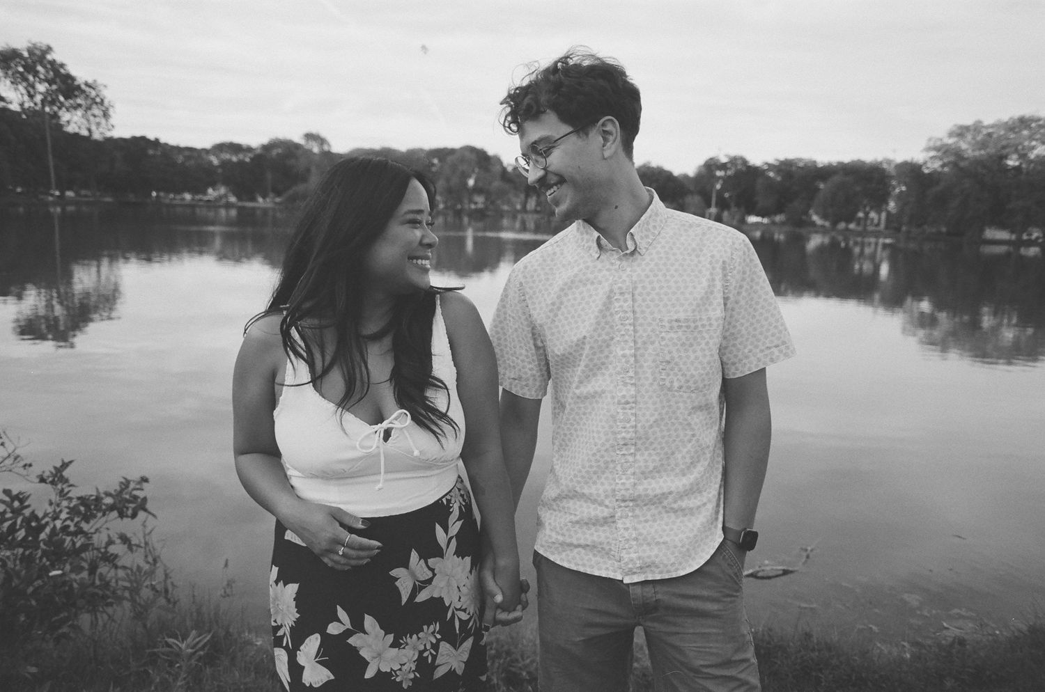 A series of black and white photos showing tender moments between a couple near a lake.