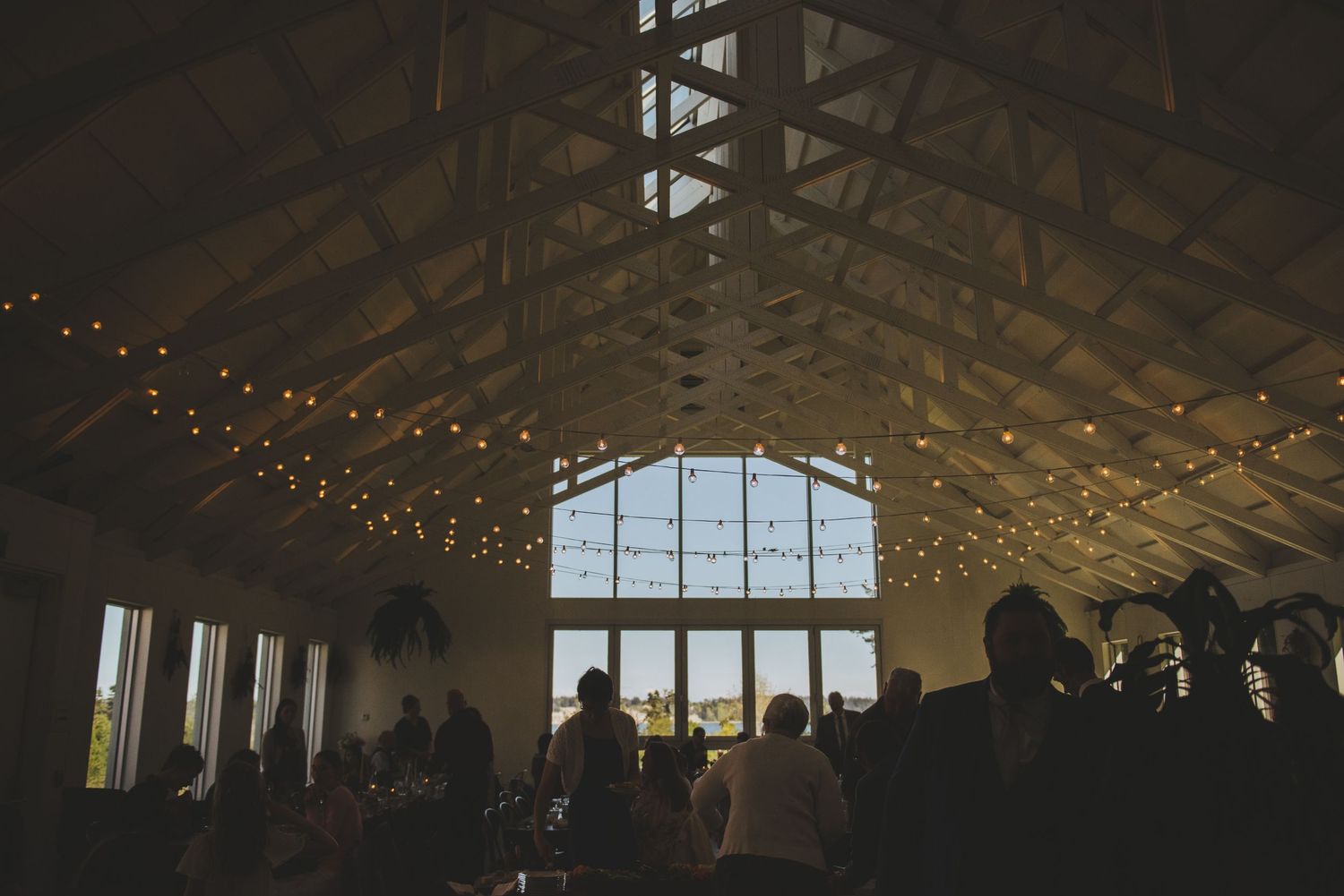 Wedding reception venue interior with string lights and large windows creating a warm atmosphere.