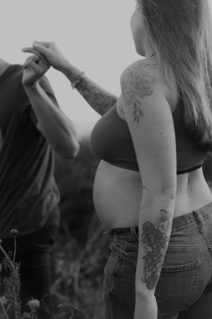 Black and white photo of couple holding hands during outdoor maternity session.