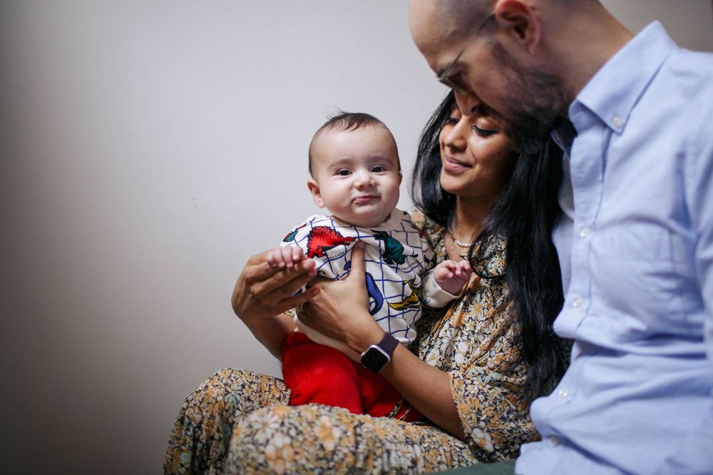 a mother and father sit on the stairs with their 6-month-old son in their home in Queen Anne Seattle