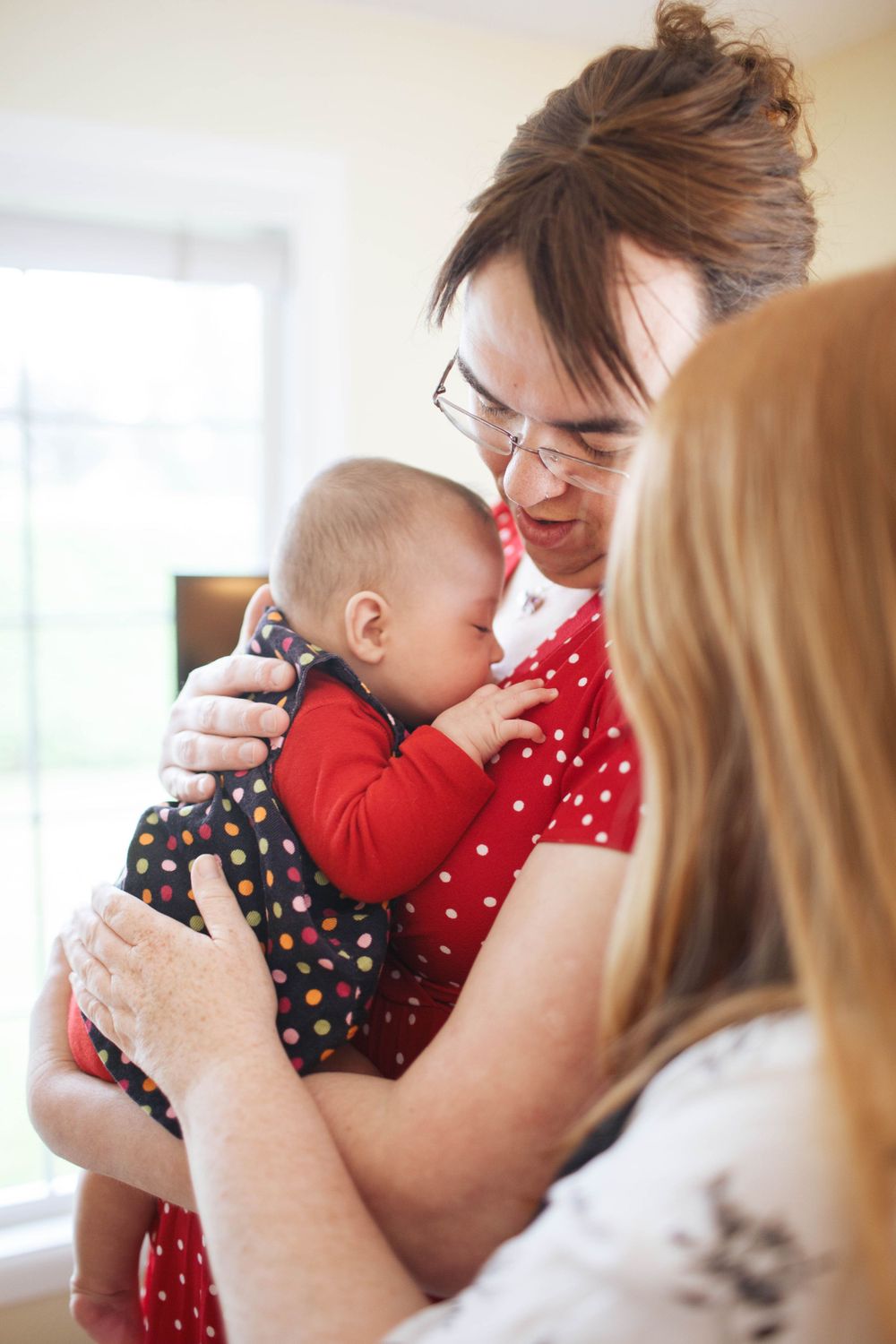 A queer couple hold their newborn daughter at an in-home family session in Everett WA