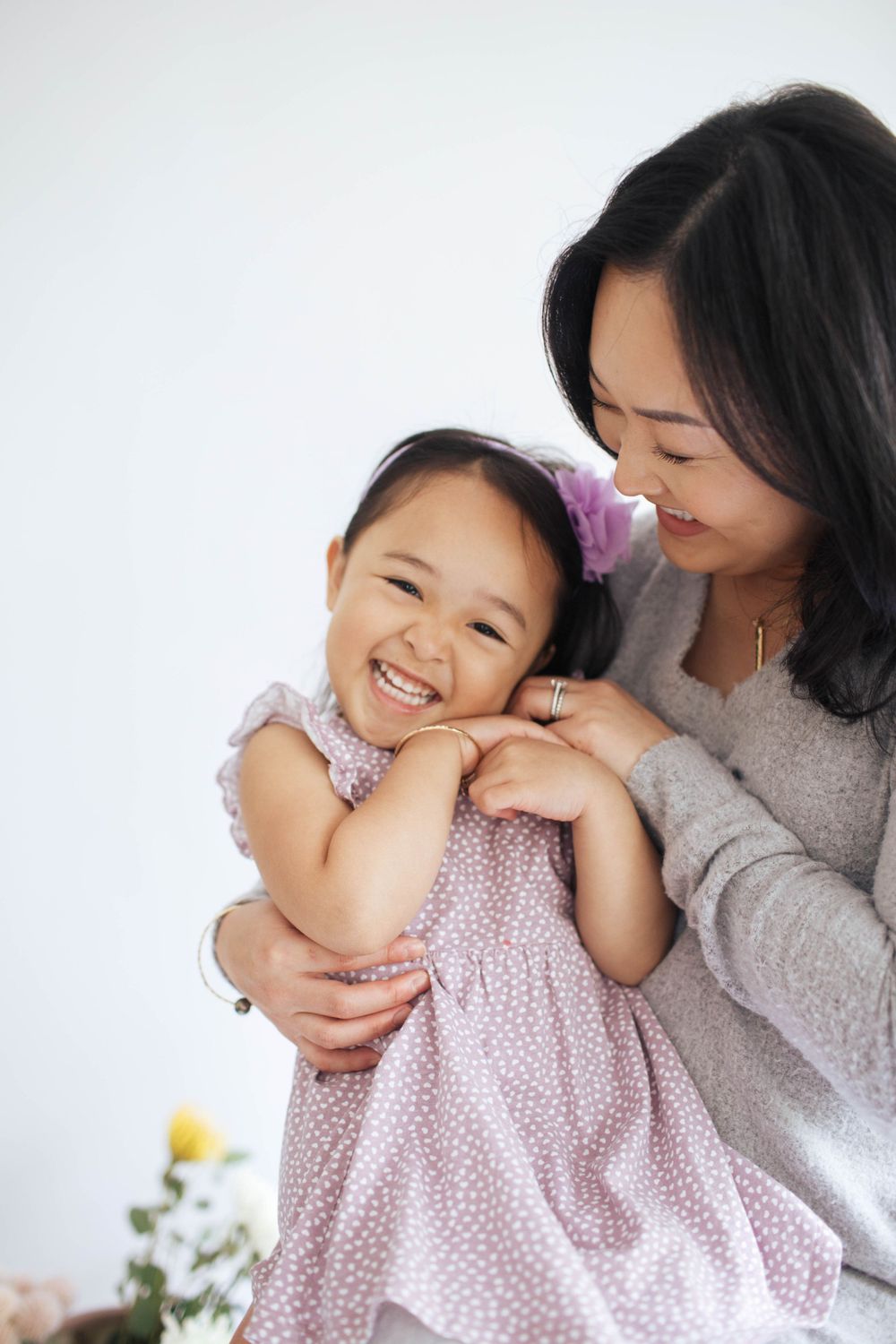 a mother tickles the chin of her daughter and an in-home family photo session