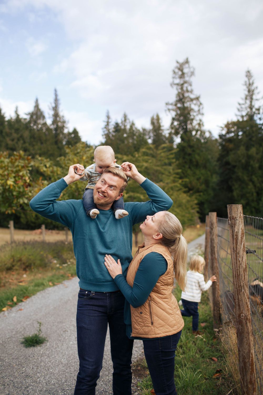 a mother and father in their front yard in Snohomish WA. The father is carrying their 6-month-old on his shoulders.