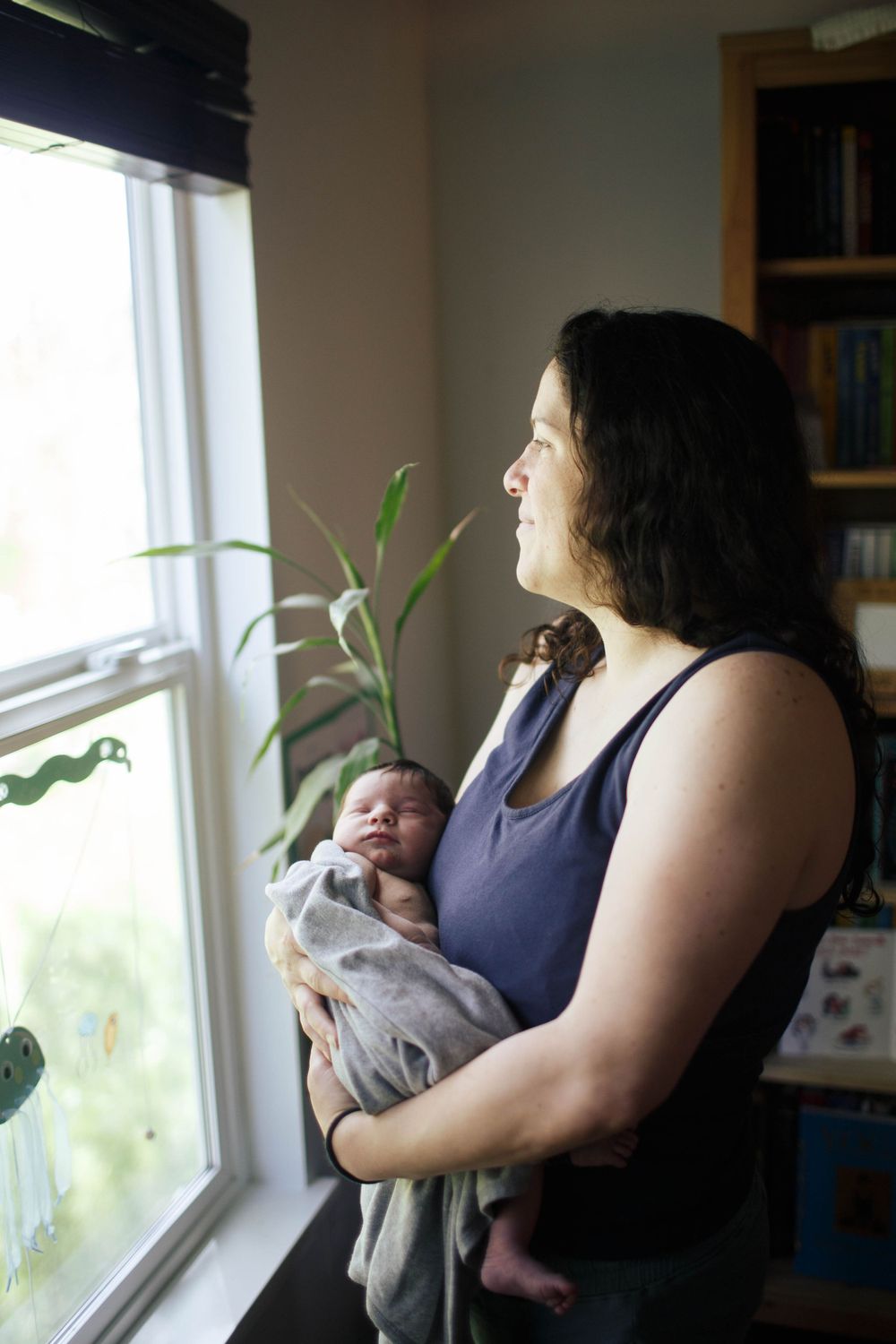 A mother holds her newborn baby as she looks out the window at her home in SIlverlake Everett WA