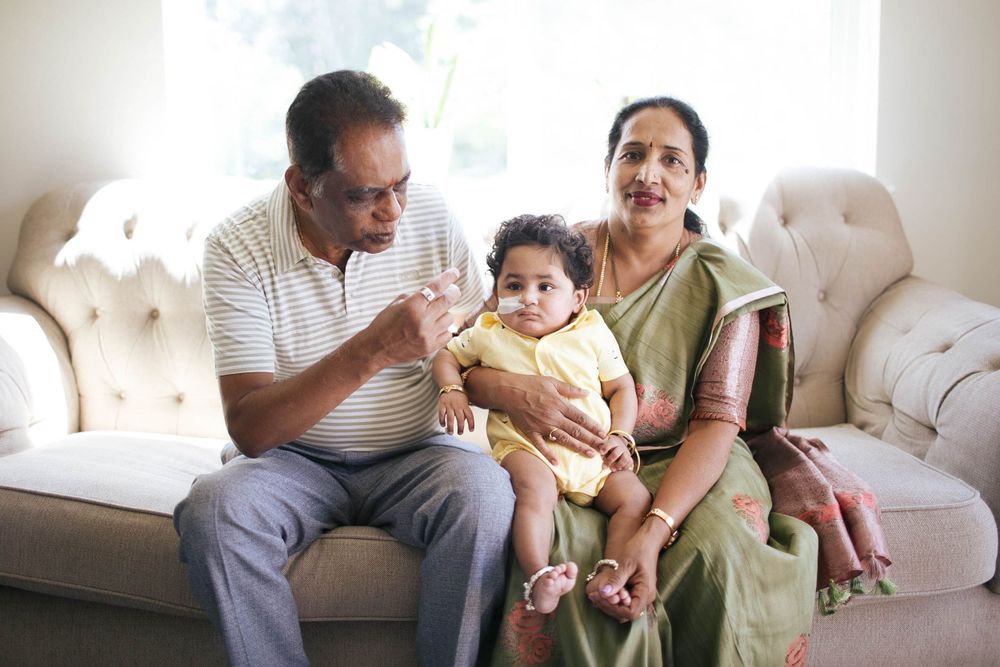 a grandfather and grandmother sit on the couch with their infant grandson in Everett WA