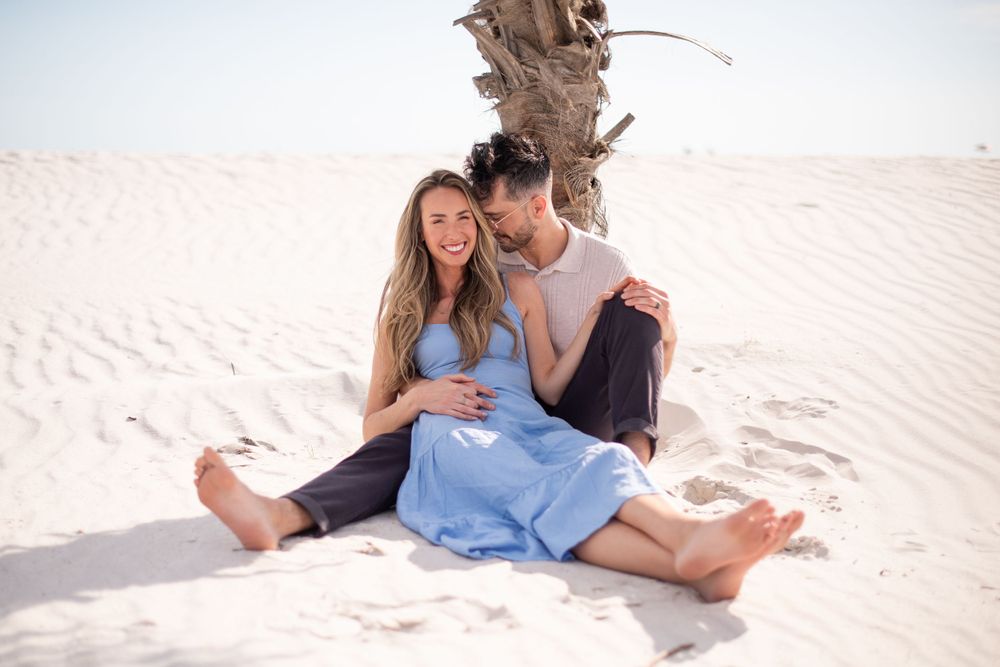 Couple sharing intimate moment while sitting on sandy beach at sunset.