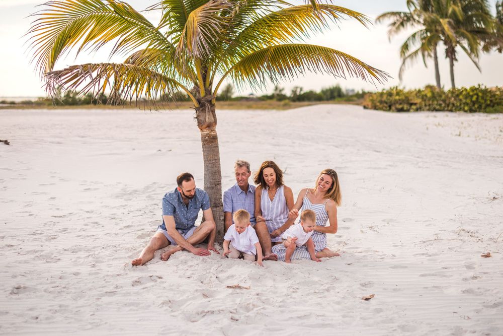 Family relaxing together on tropical beach with palm trees and ocean views.