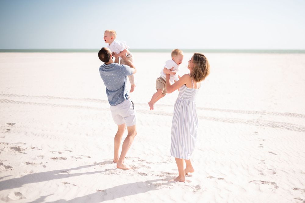 Family members walking together on bright white sandy beach near ocean.