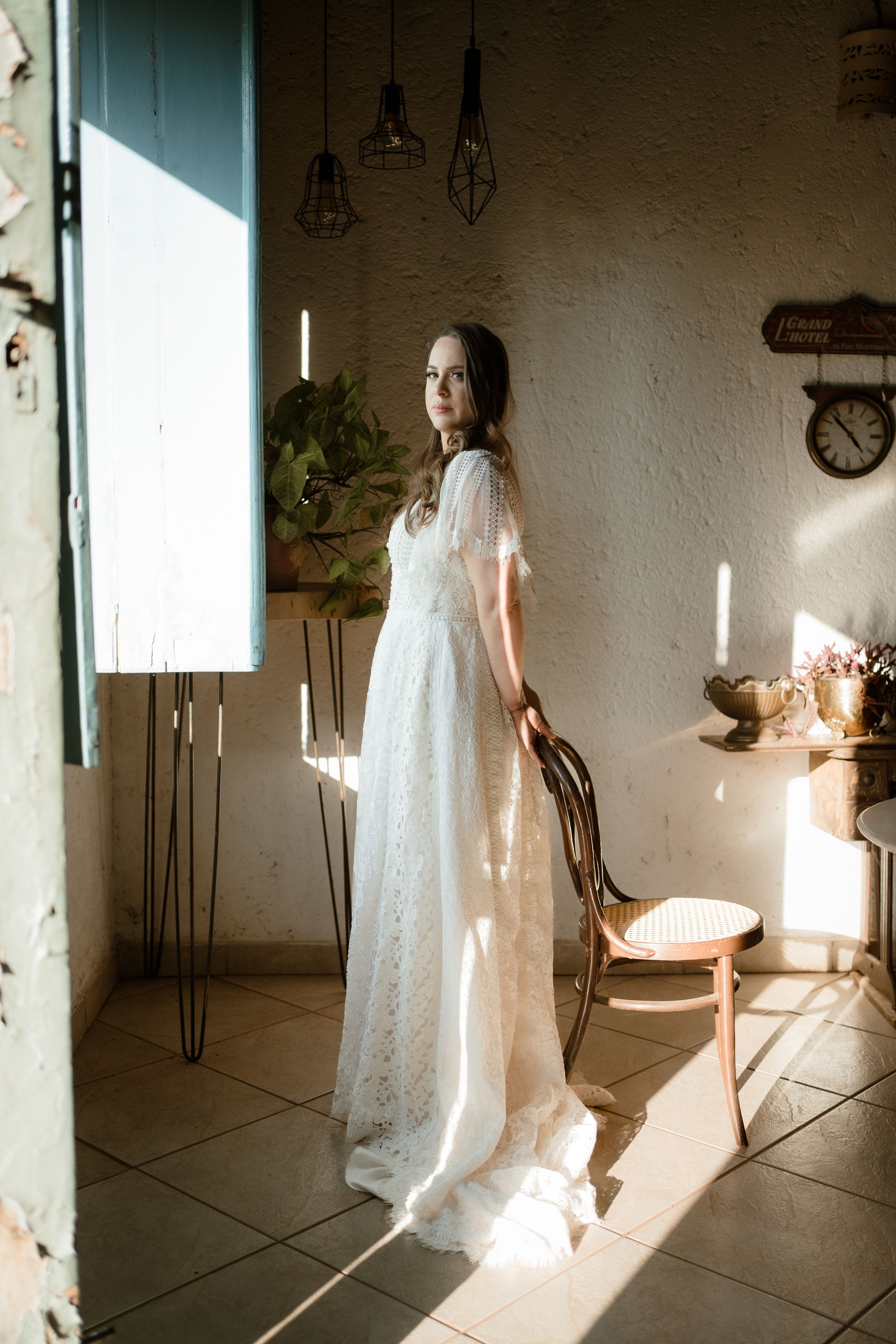 Bridal portrait in white lace dress with dramatic window lighting.