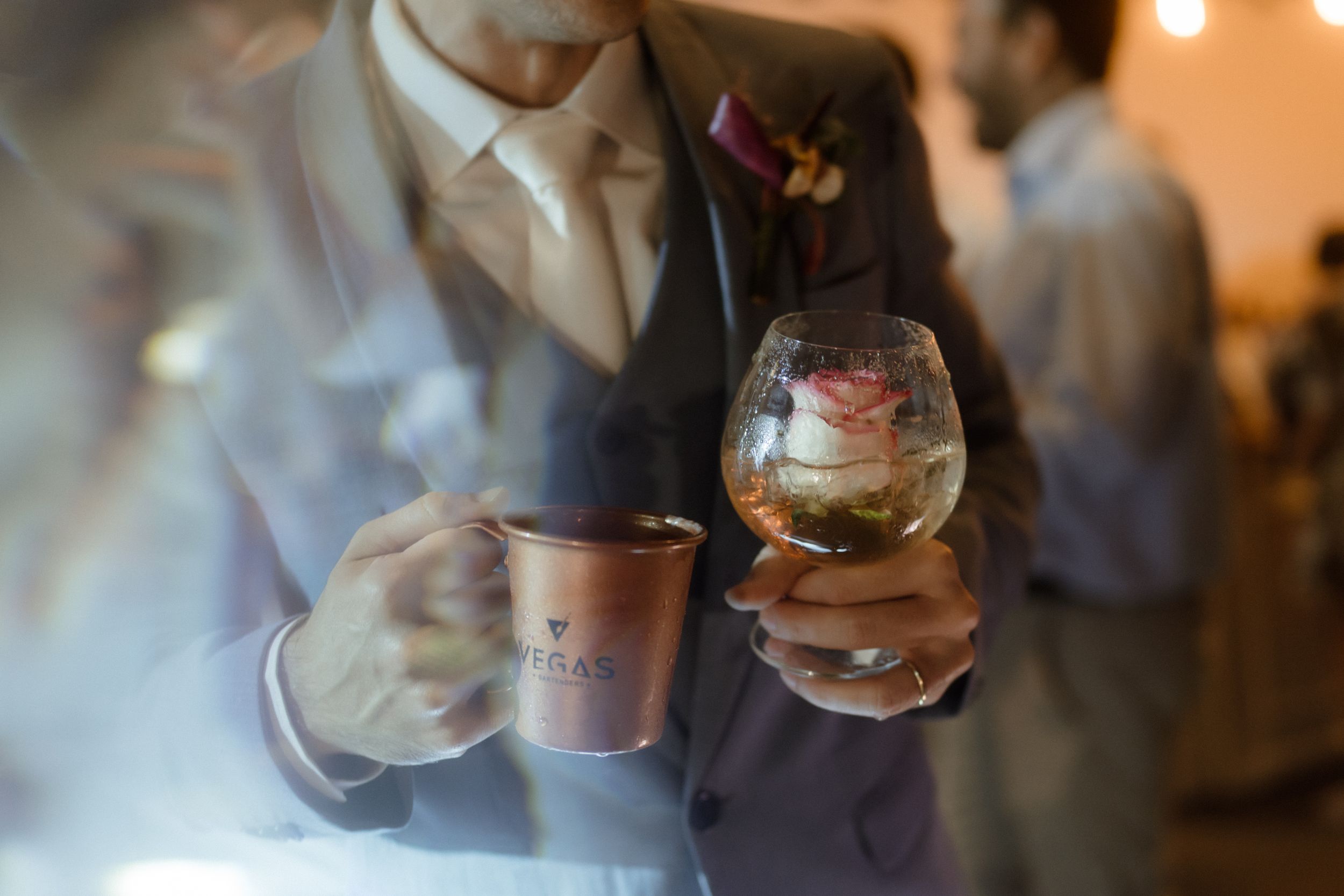 Person holding a wine glass in soft focus at an evening event.