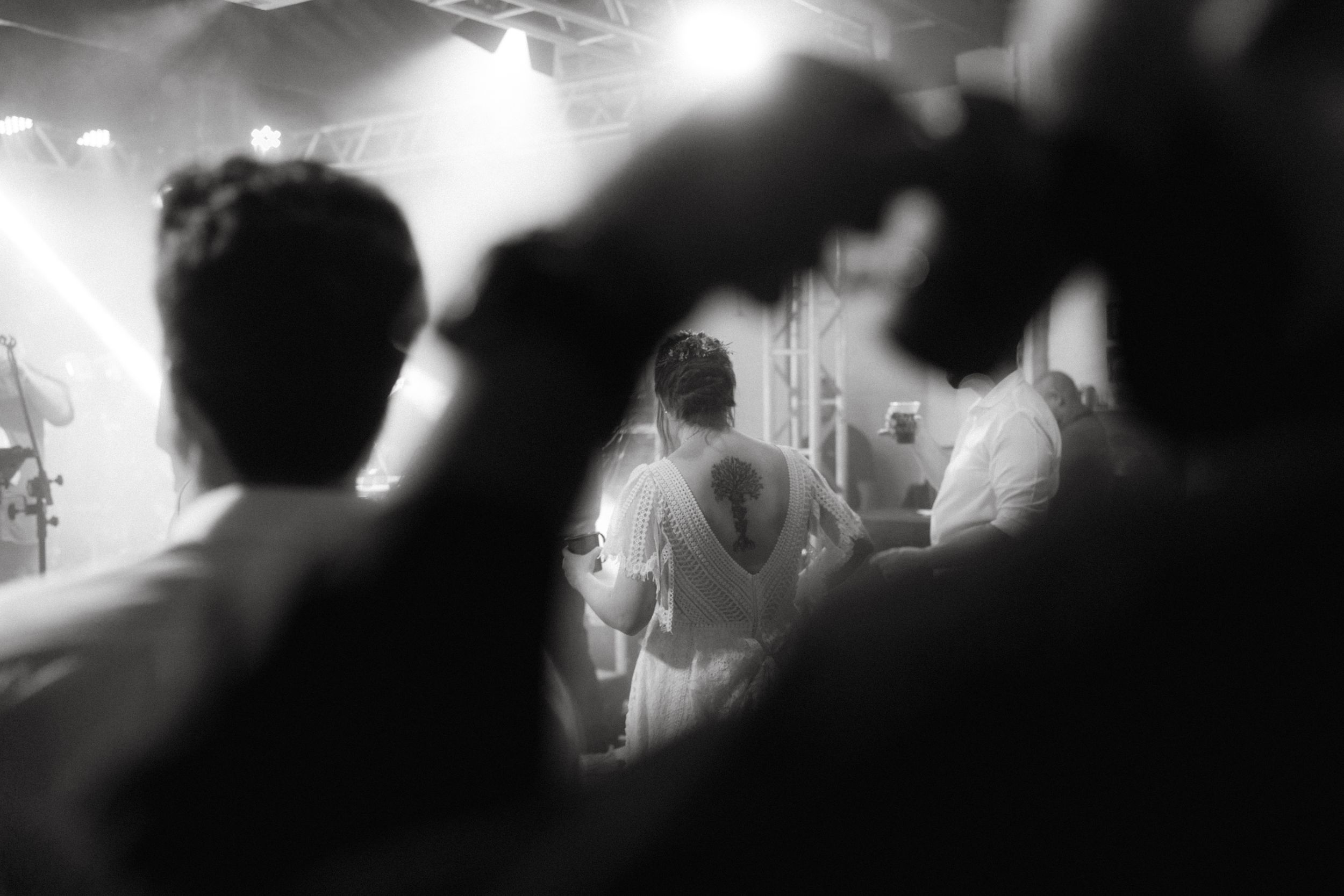 Black and white photo of silhouetted wedding guests dancing in a dimly lit reception venue.