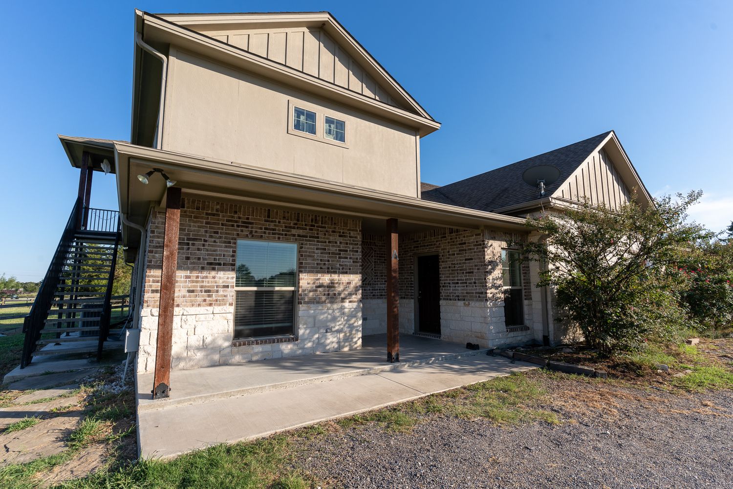 Modern two-story home with stone and beige siding exterior and covered front porch.