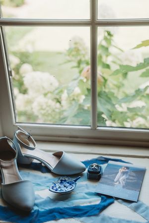 Rustic tea set with blue cloth and natural light streaming through window panes creates a serene morning scene.