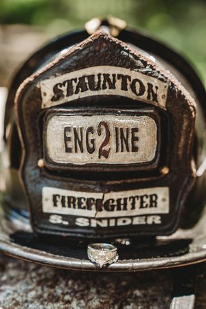 Close-up of a Staunton Engine 2 firefighter helmet belonging to S. Snider with a diamond ring resting on it.
