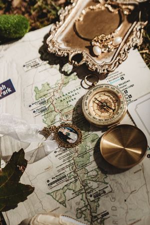 Vintage compass and locket on Shenandoah National Park map with ornate silver tray, adventure travel flat lay.