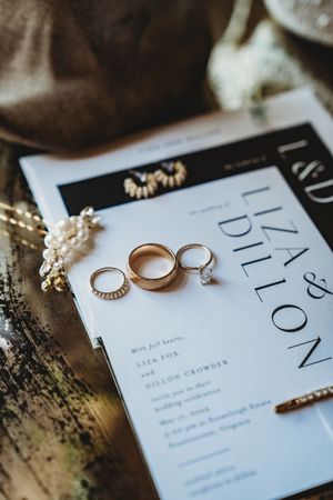 Wedding rings and invitation details captured in an artistic flat lay composition with elegant typography and soft lighting.