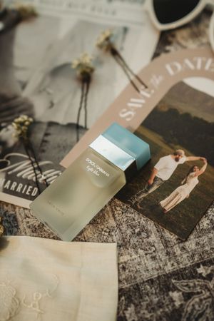Dolce & Gabbana Light Blue perfume bottle resting on wedding save the date cards and dried flowers.