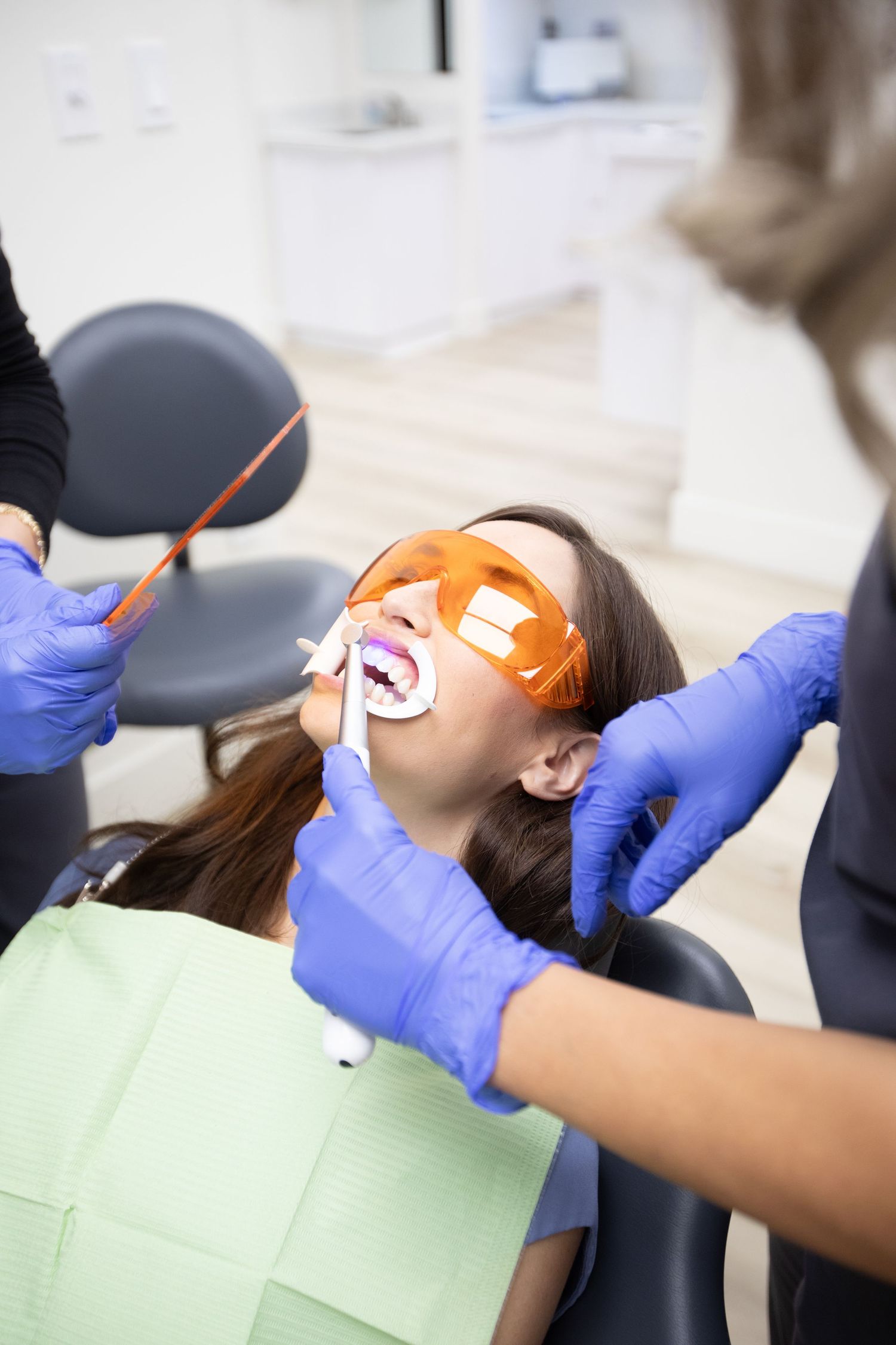 Dental patient receiving treatment while wearing protective orange eyewear.