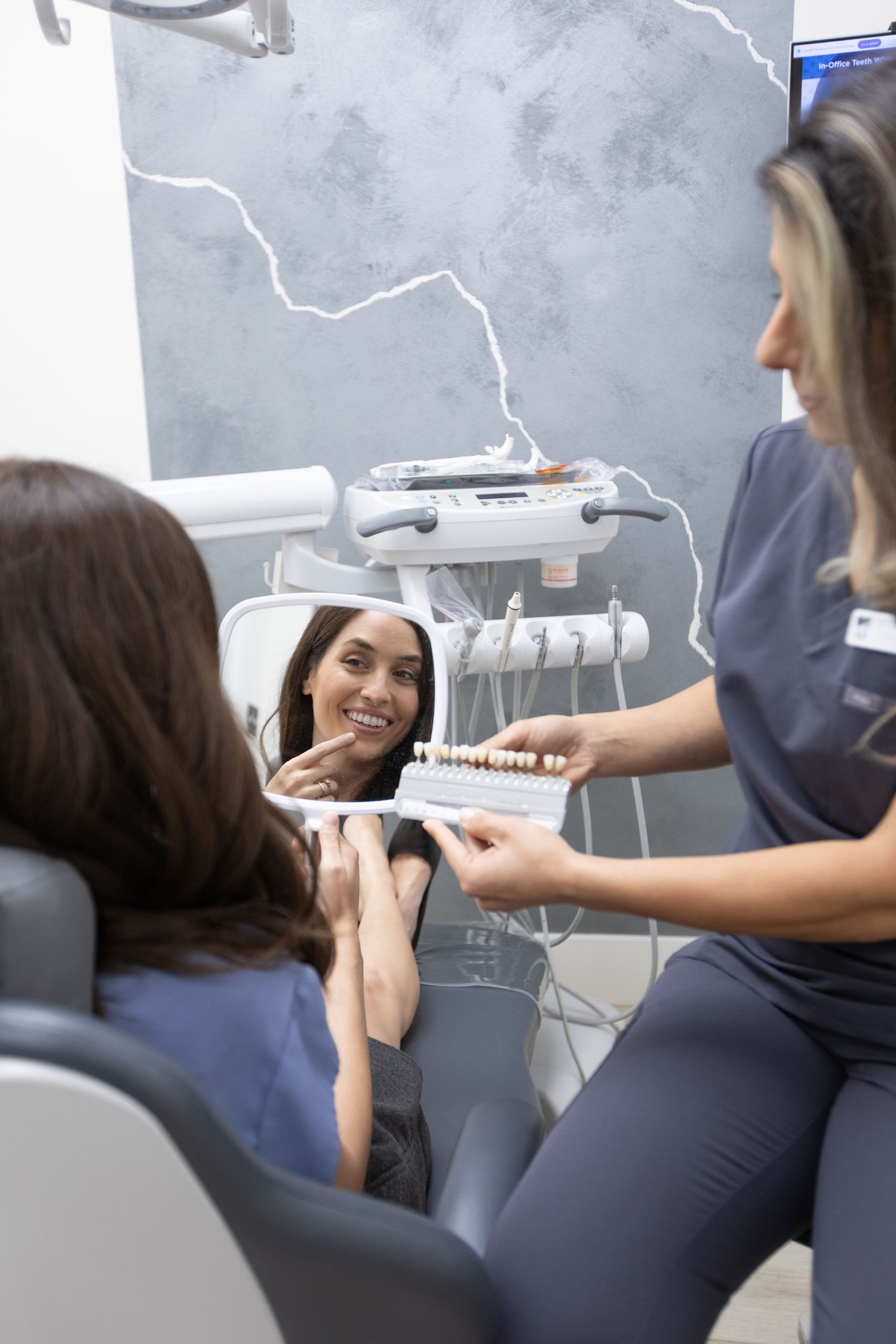 Dental patient checking smile in mirror during consultation.