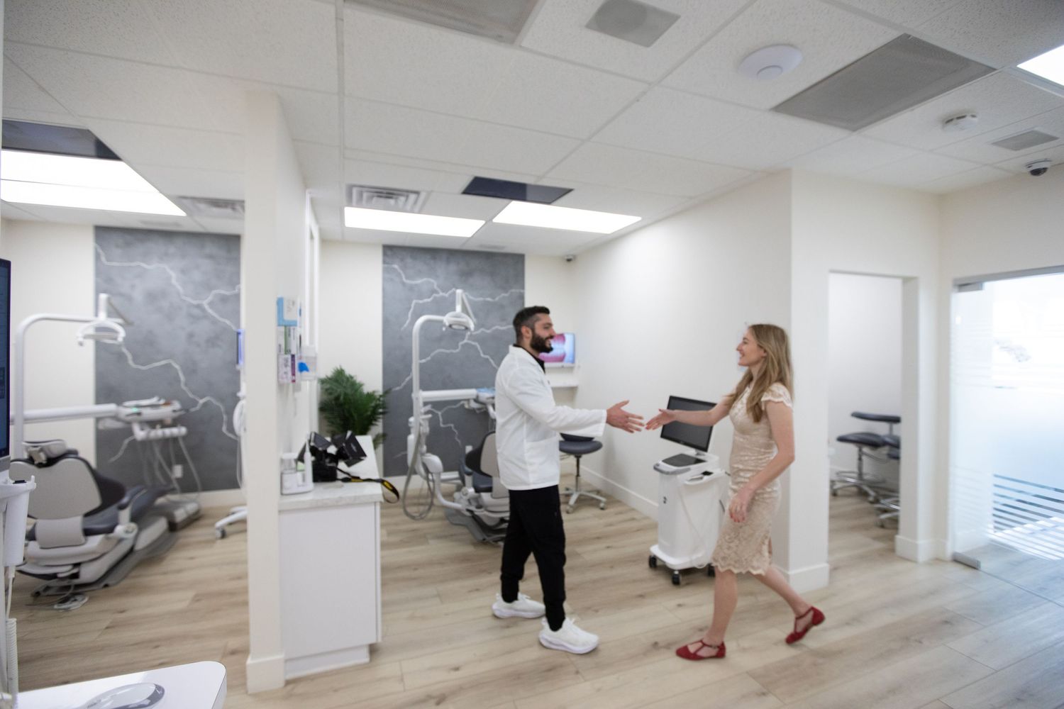 Healthcare professionals greeting in modern dental office with light wood floors.