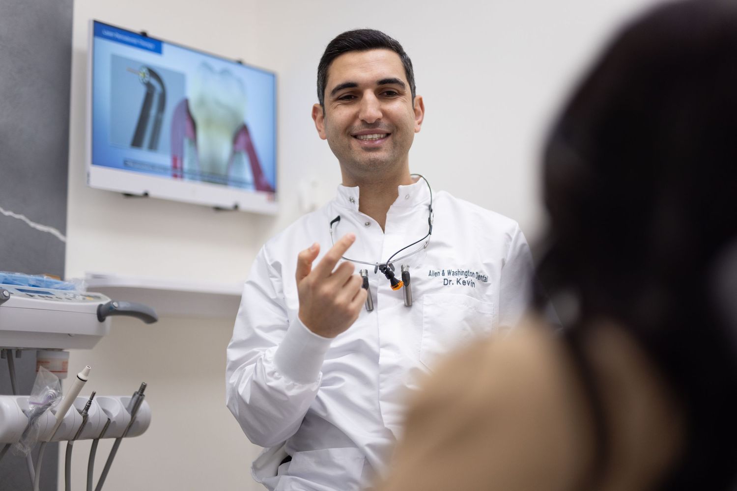 Healthcare professional in white coat demonstrating dental tools in modern examination room.