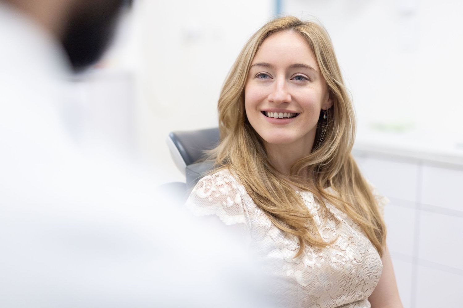 Patient seated in dental chair during consultation in bright medical office.