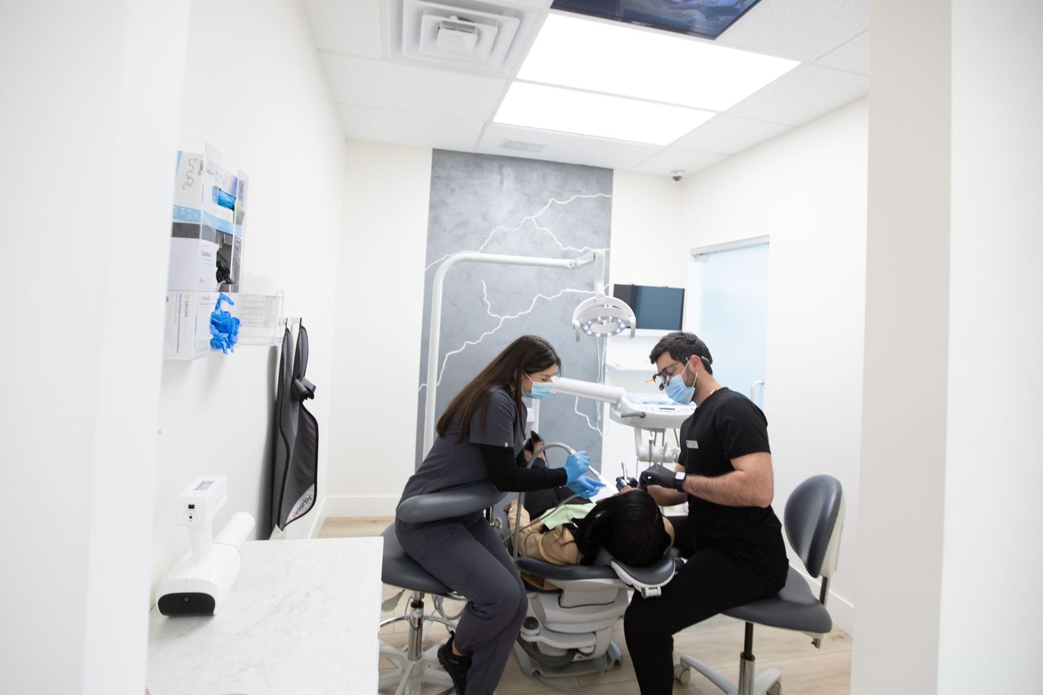 Dental procedure in progress in modern treatment room with equipment.