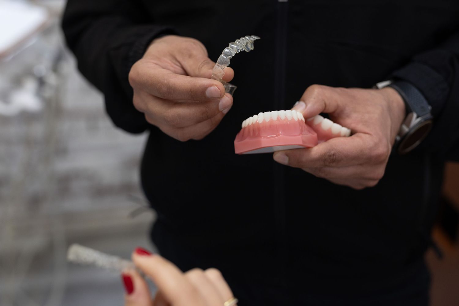Close-up of hands examining dental tools and dentures.