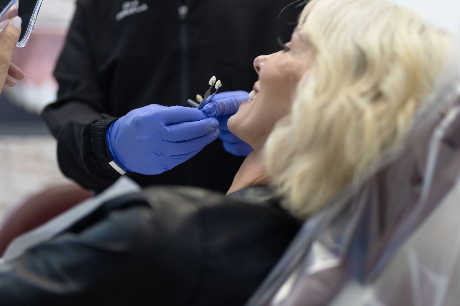 A dentist with blue gloves performing a dental procedure on a patient.