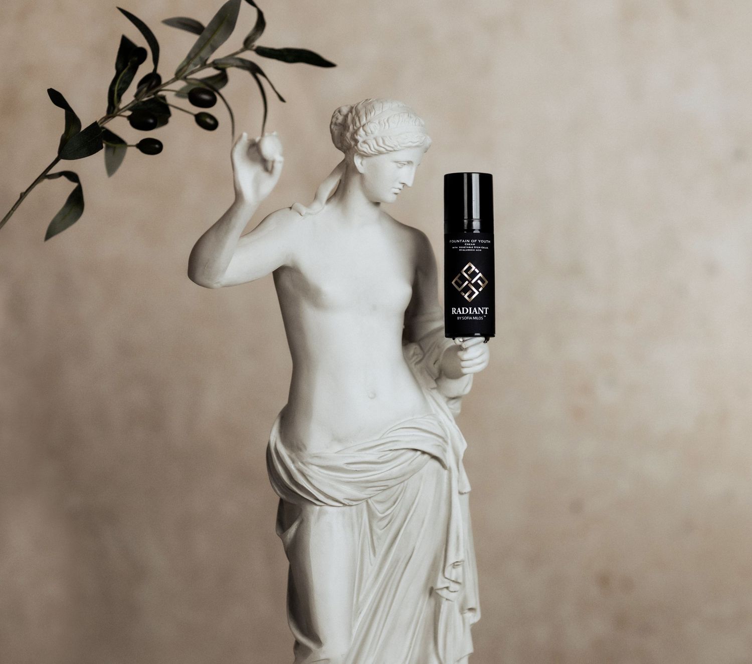 Classical white statue posed with black cosmetic bottle against neutral background.