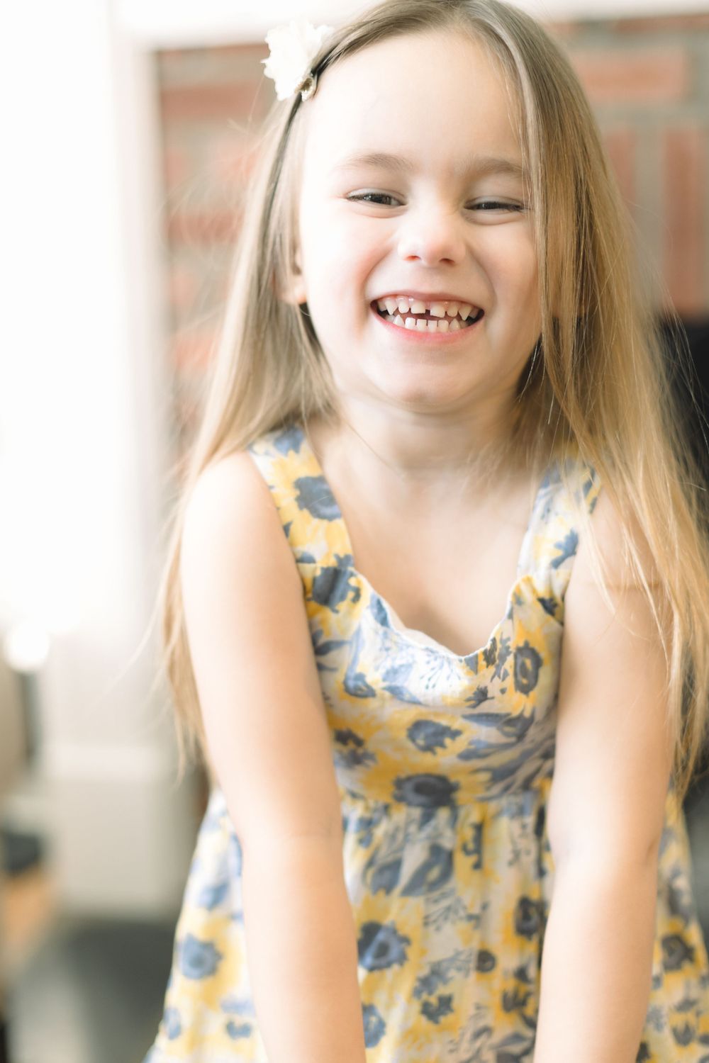A joyful moment captured as a child in a yellow floral dress laughs with pure delight.