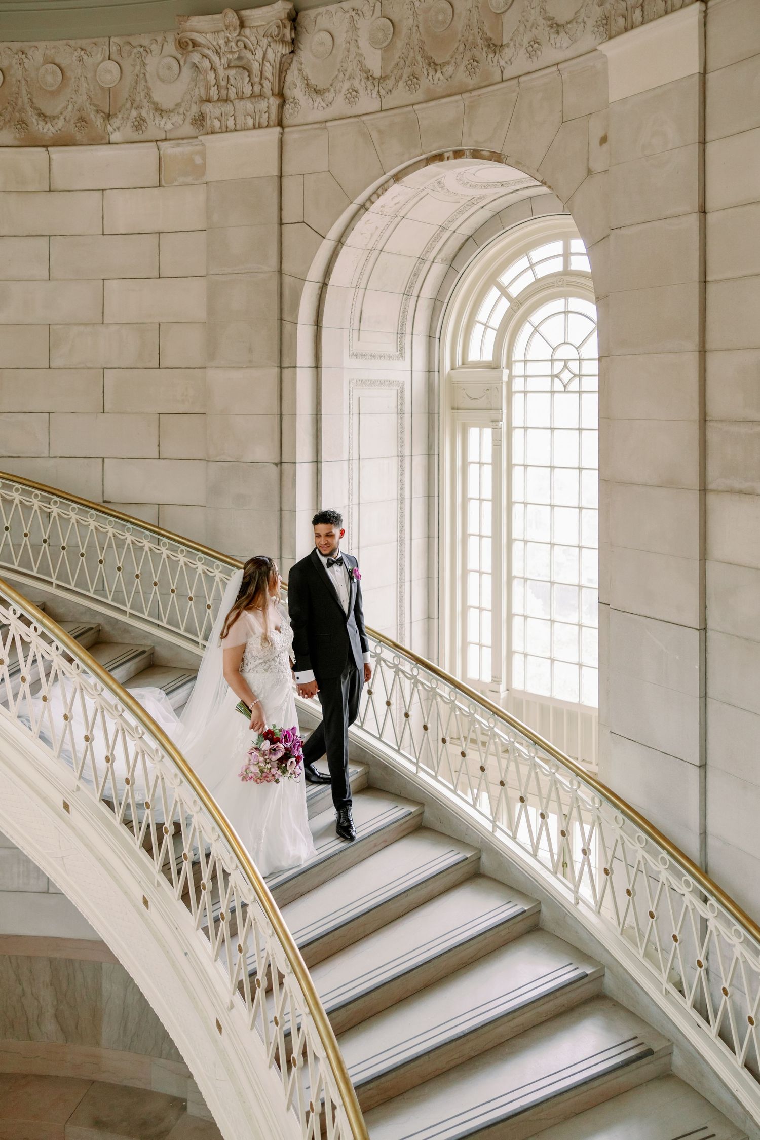 Elegant white marble staircase with ornate railings and arched windows in a grand venue at Hartford City Hall.