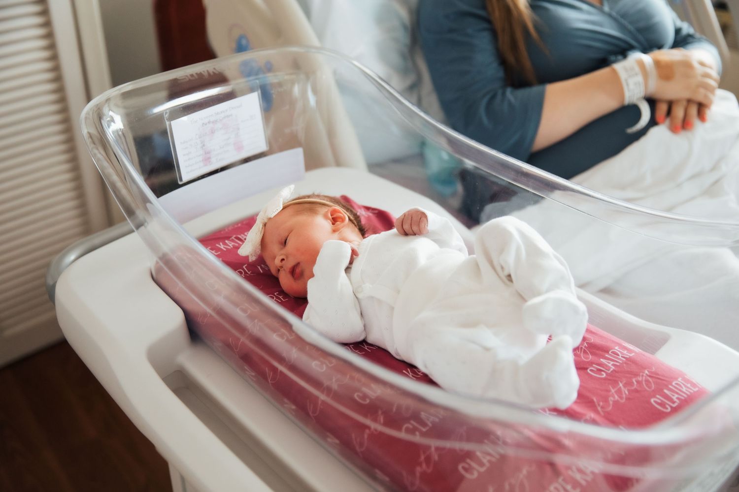 Newborn baby resting in clear hospital bassinet with pink padding. fresh48. Newport hospital baby girl