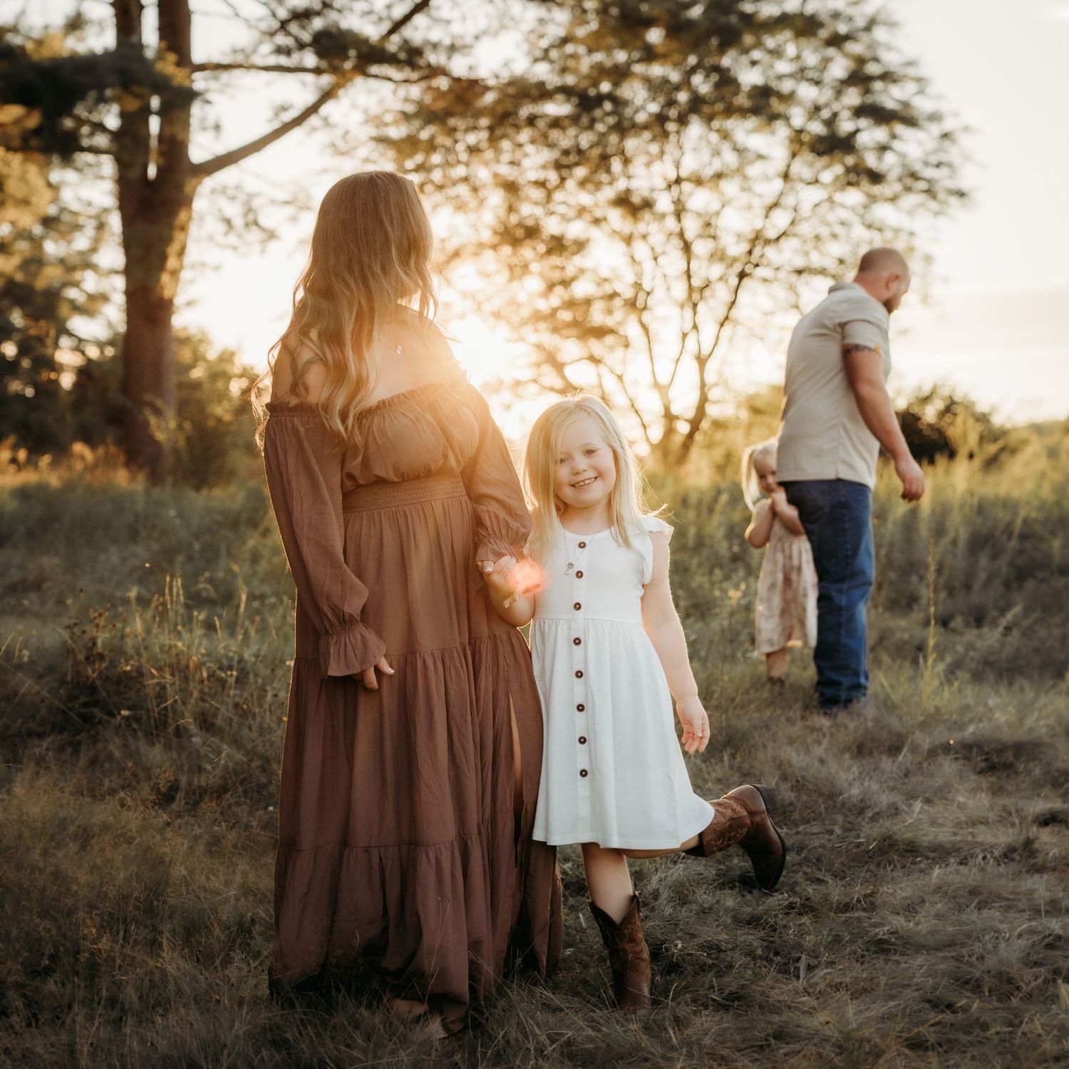 Mother and child sharing tender moment together in sunlit meadow at sunset.