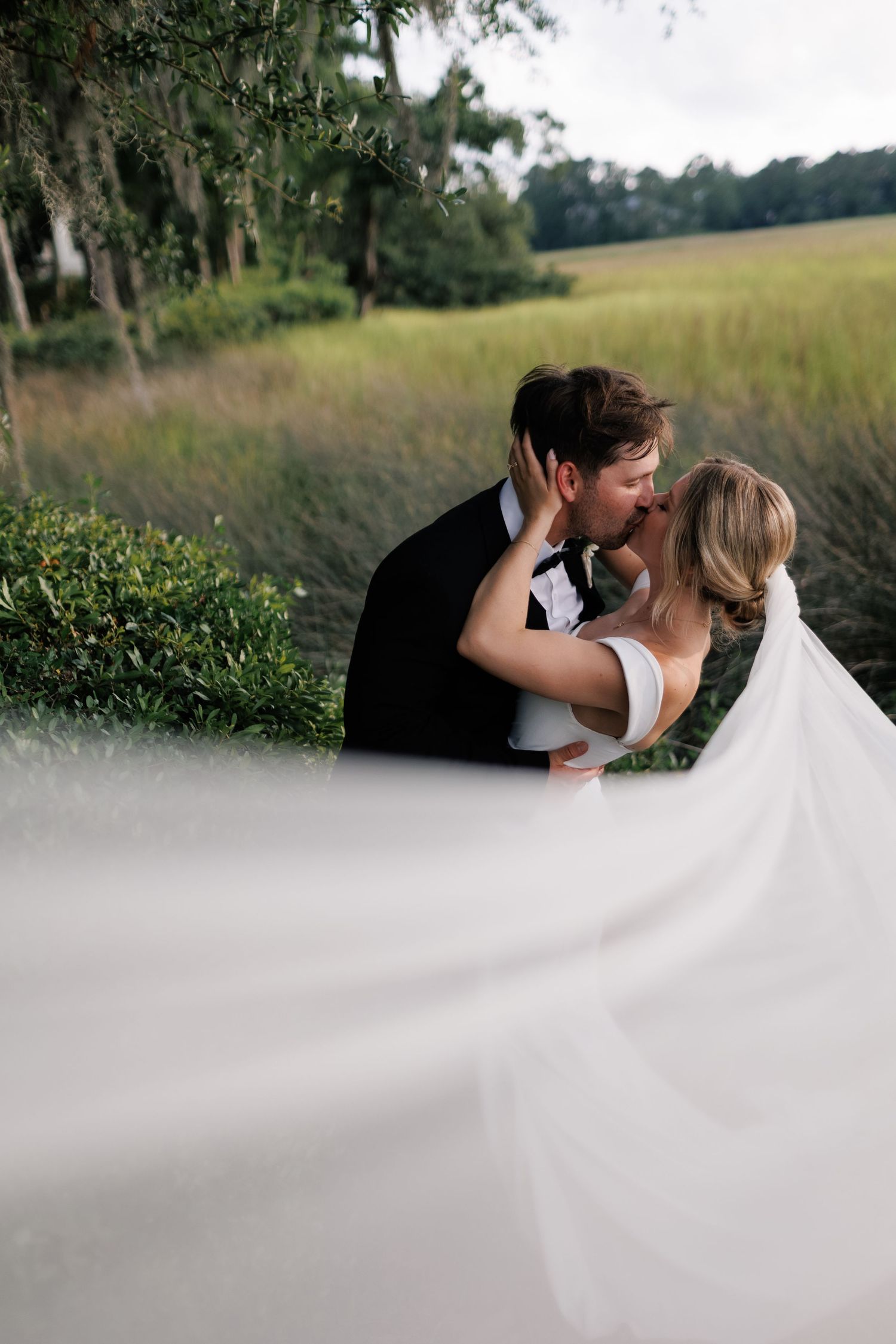 A young bride and groom sharing an intimate kiss, during the golden hour at Creek Club at I'on, in Mt. Pleasant, SC