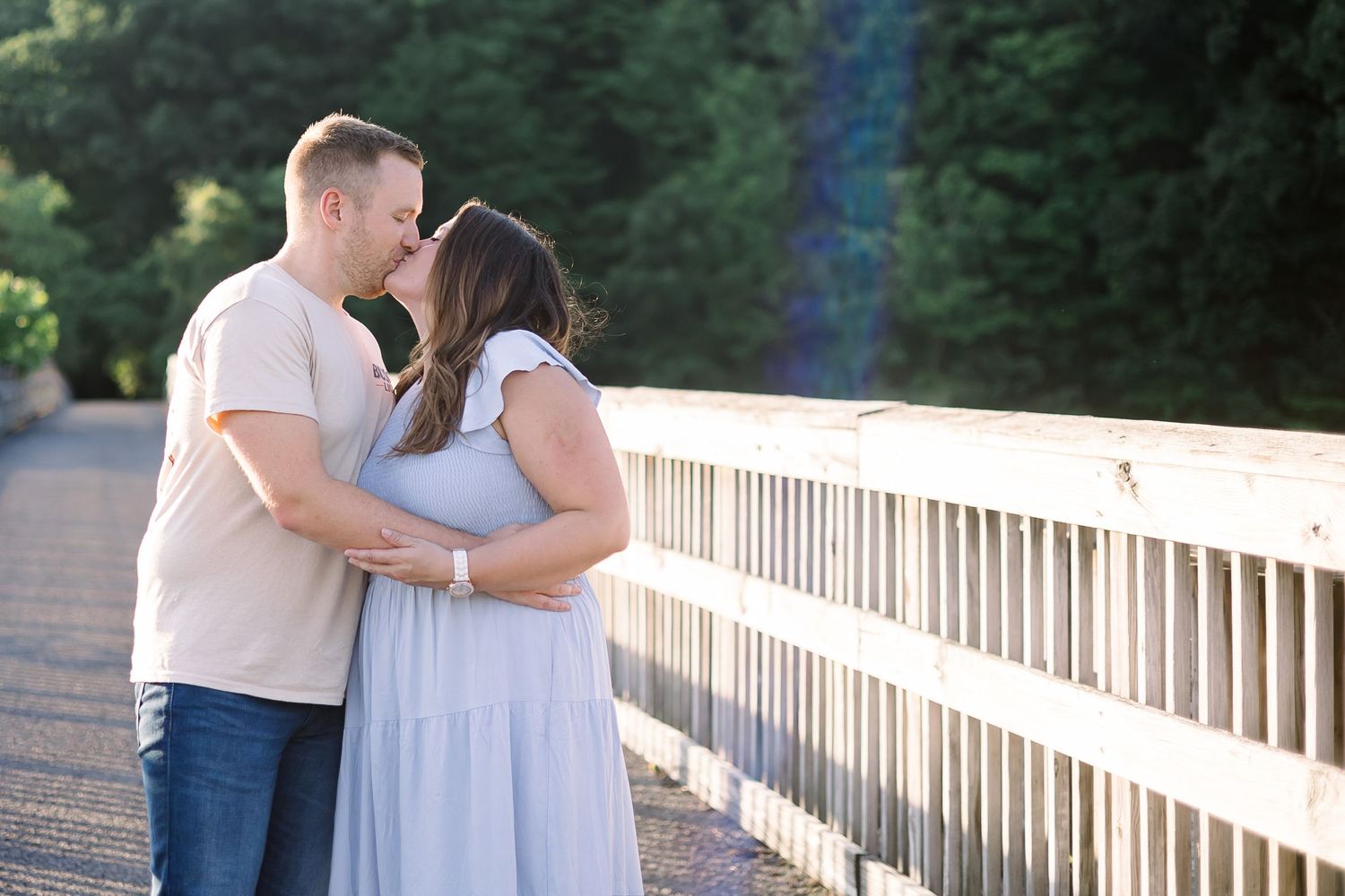 Romantic couple shares tender moments on a wooden dock by a serene lake at sunset.