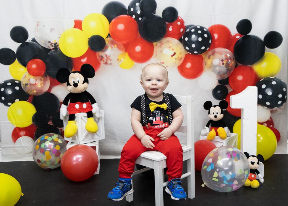 Mickey Mouse themed birthday setup with red, yellow and black balloon arch decorations.