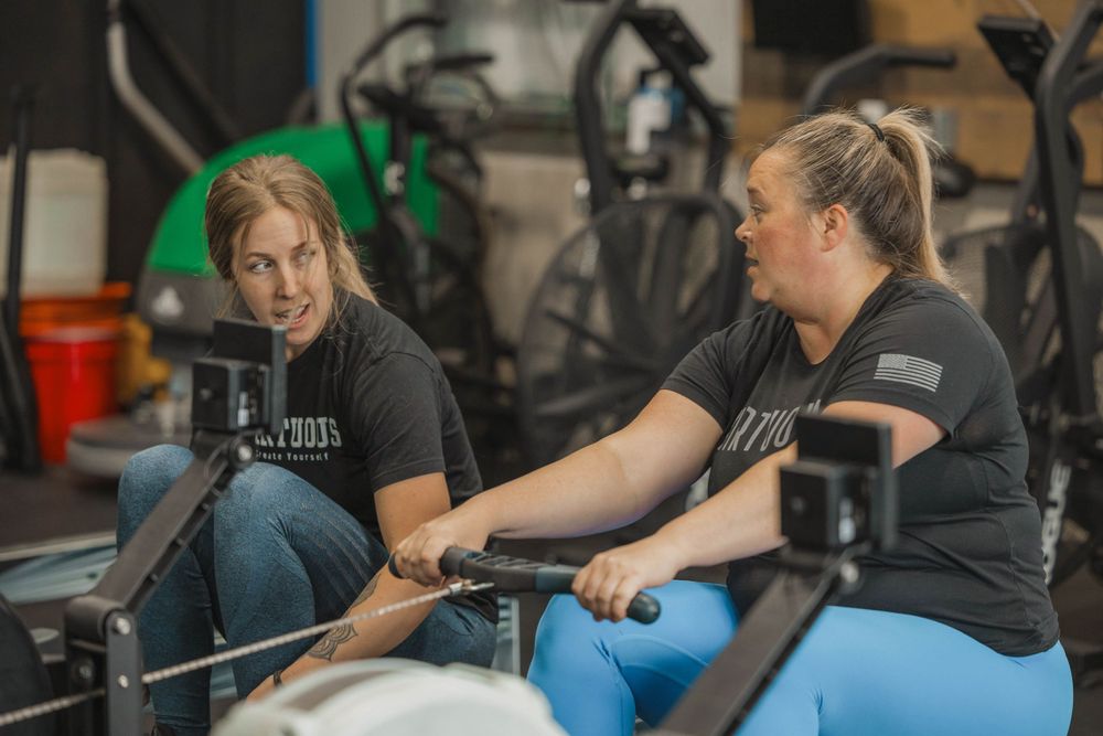 Two athletes having a discussion while seated on workout equipment in gym setting.