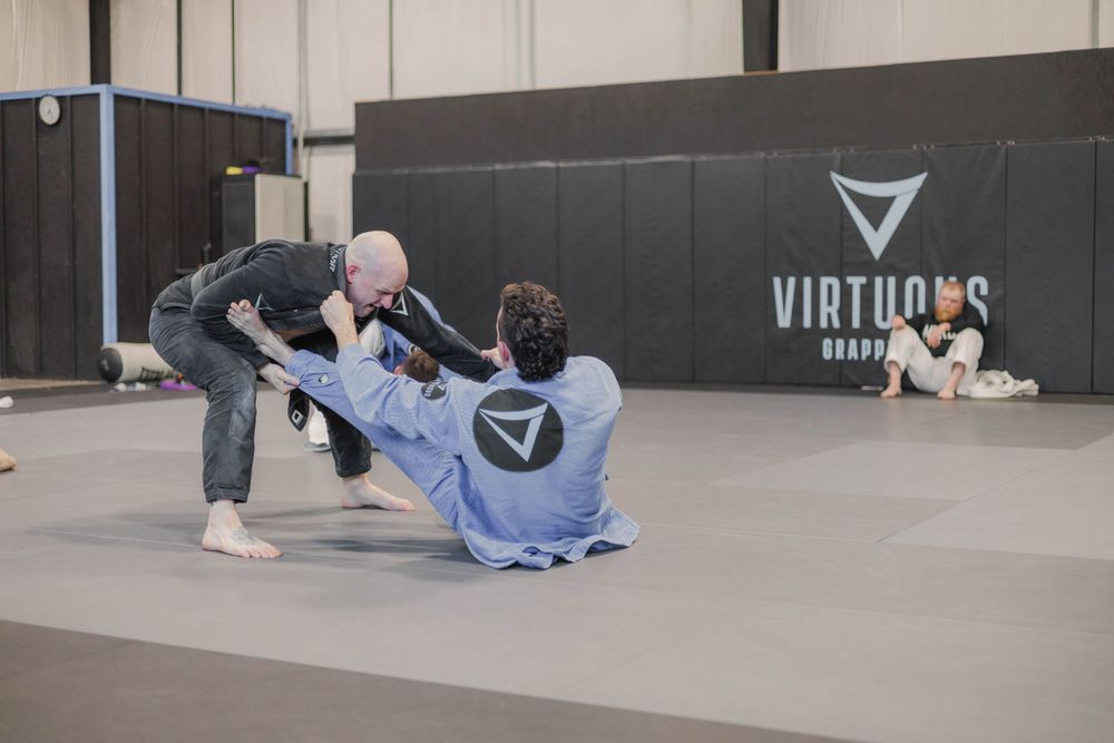 Training partners practicing leg lock defense positions during a grappling session.