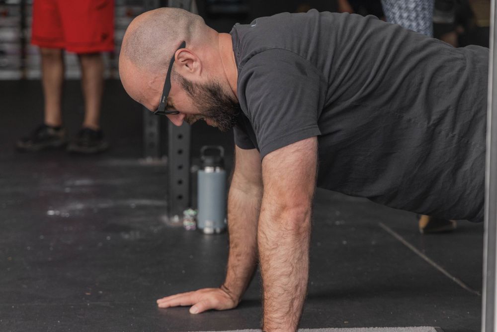 Person performing plank exercise on dark gym floor during workout.