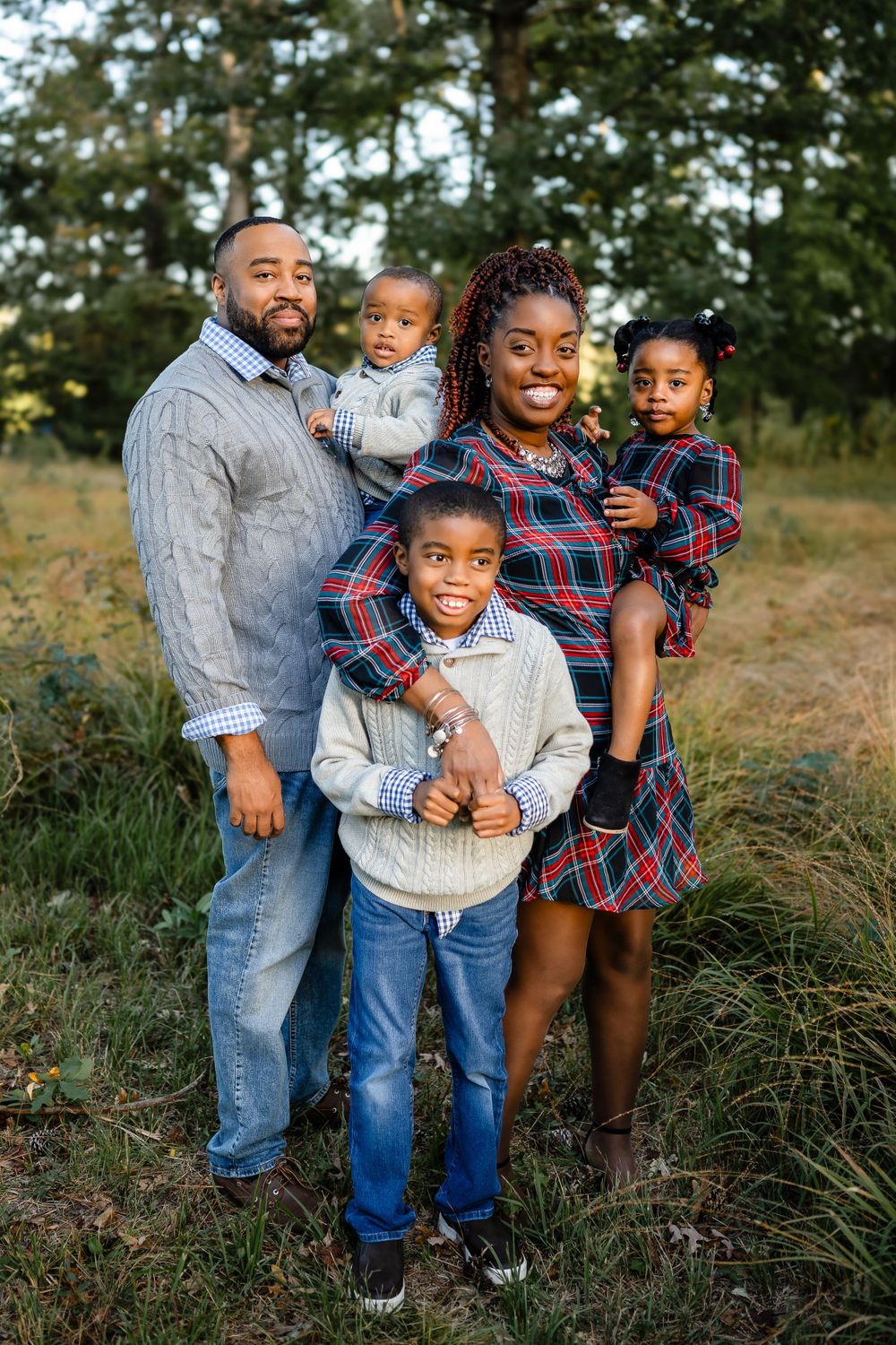 Beautiful family portrait outdoors with five members wearing coordinated casual outfits.